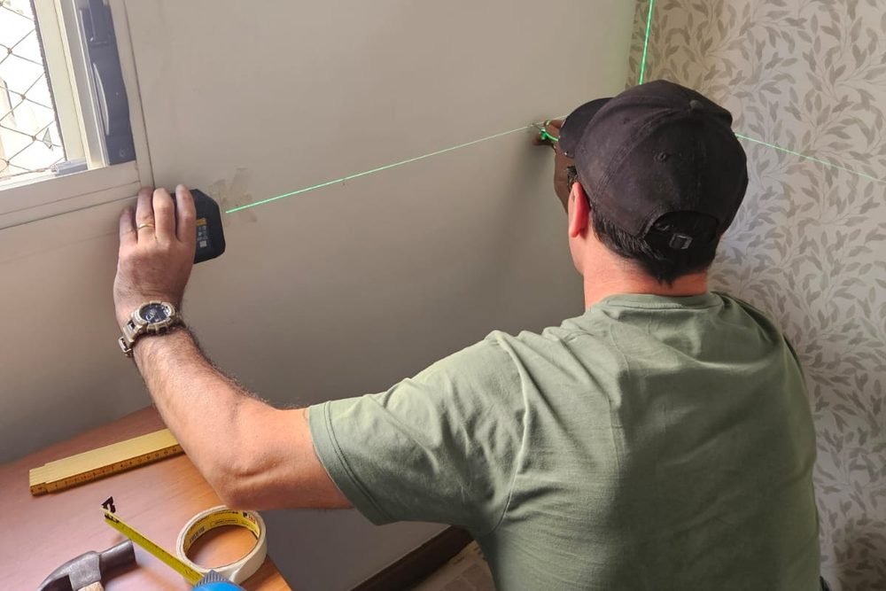 Montador da Monta Tudo Móveis marcando a parede com nível a laser